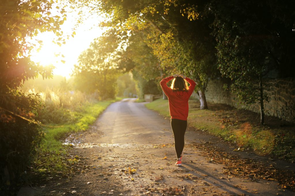 Woman walking on forest path during early evening