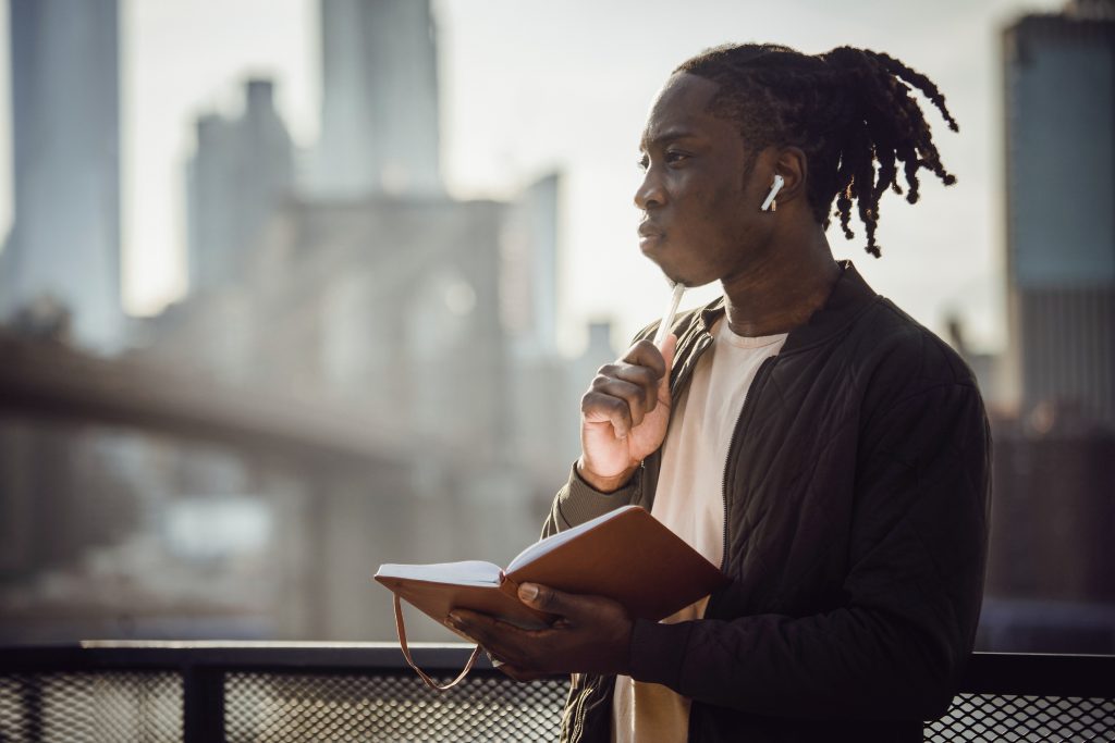 Man pausing with notebook and earphones