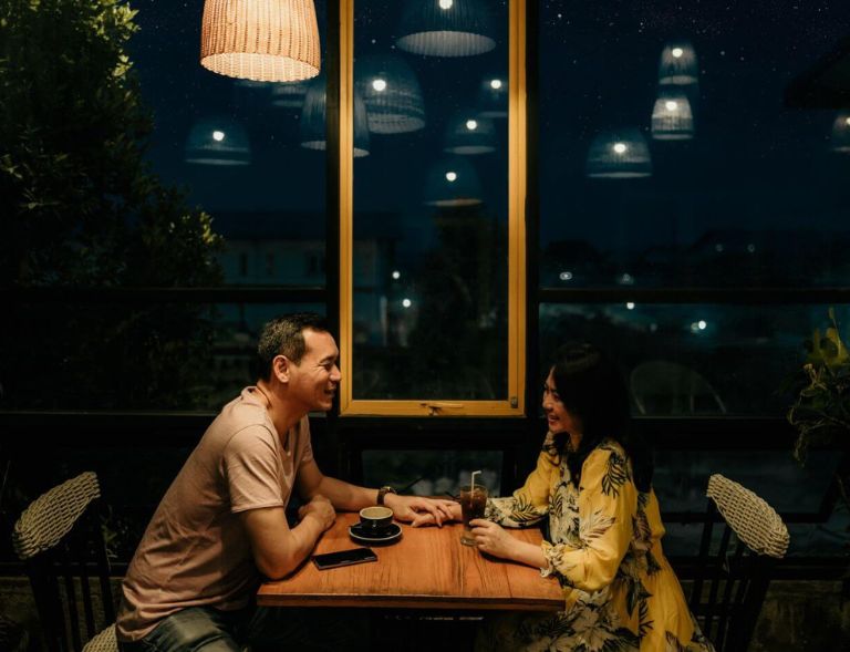 A couple enjoying a coffee and soda over a date at a restaurant in the evening