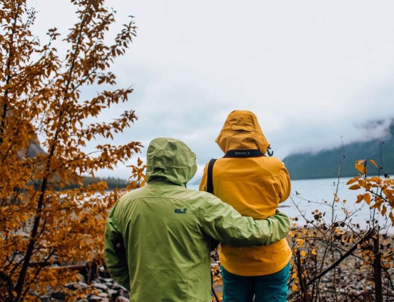 A photograph of a couple from the back as they look out into nature while on a hike.